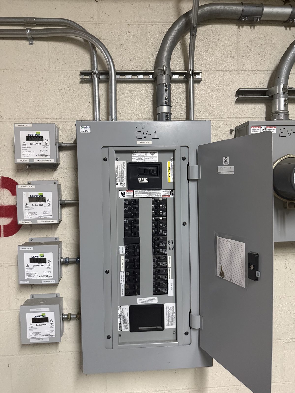 Dedicated EV charging panel with per-space sub-meters and conduit runs