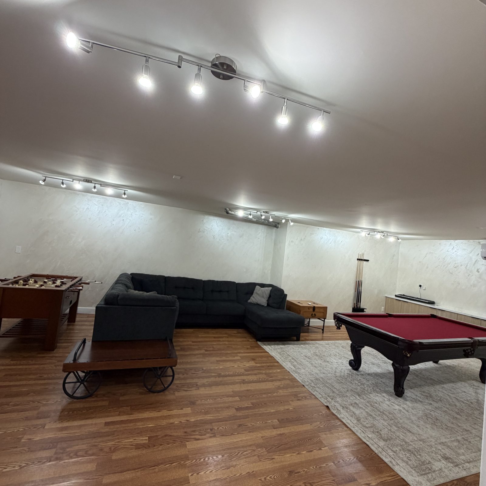 Multi-head track lighting installed in a finished game room with pool table
