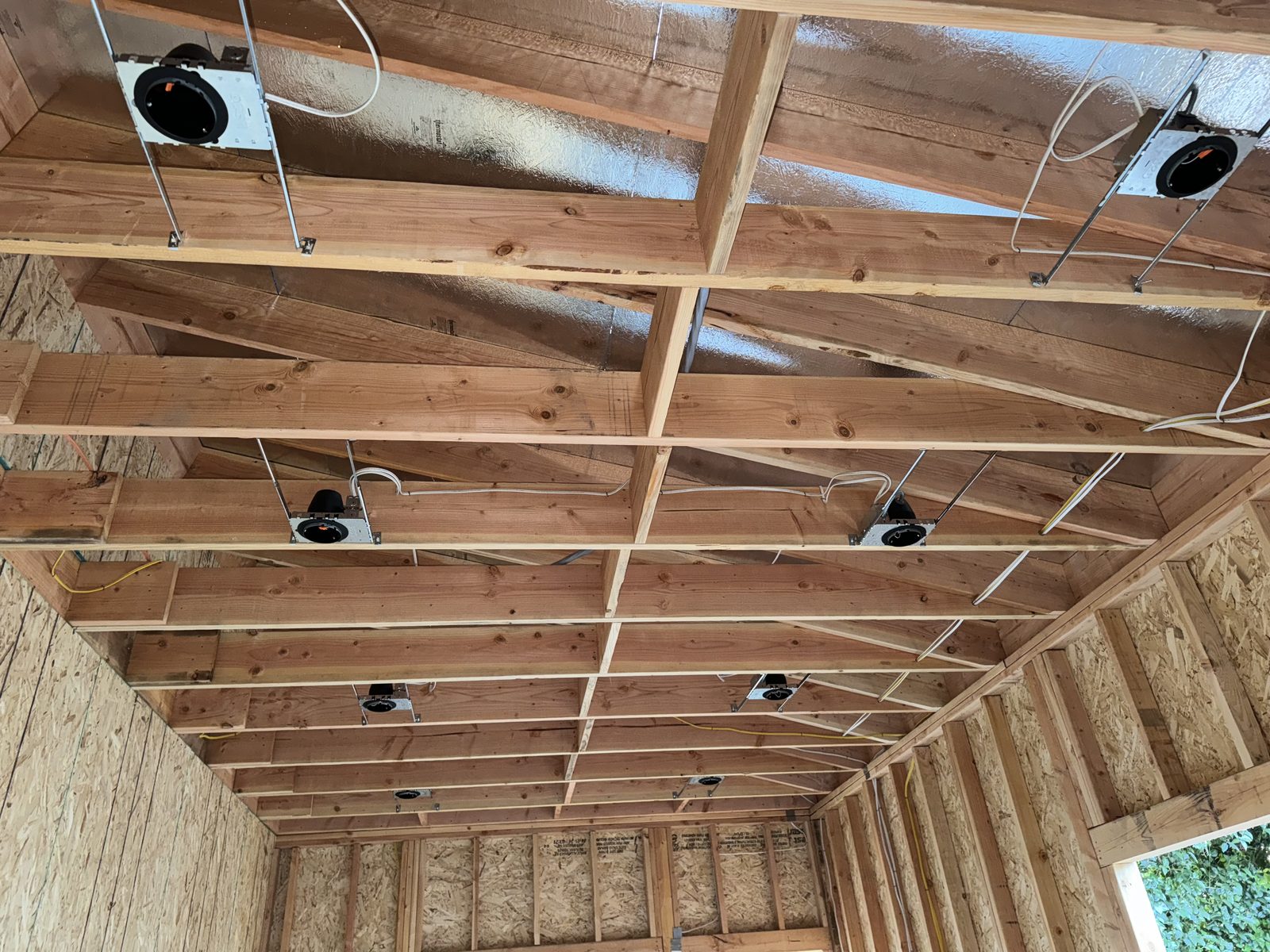 Recessed lighting housings installed across open ceiling framing
