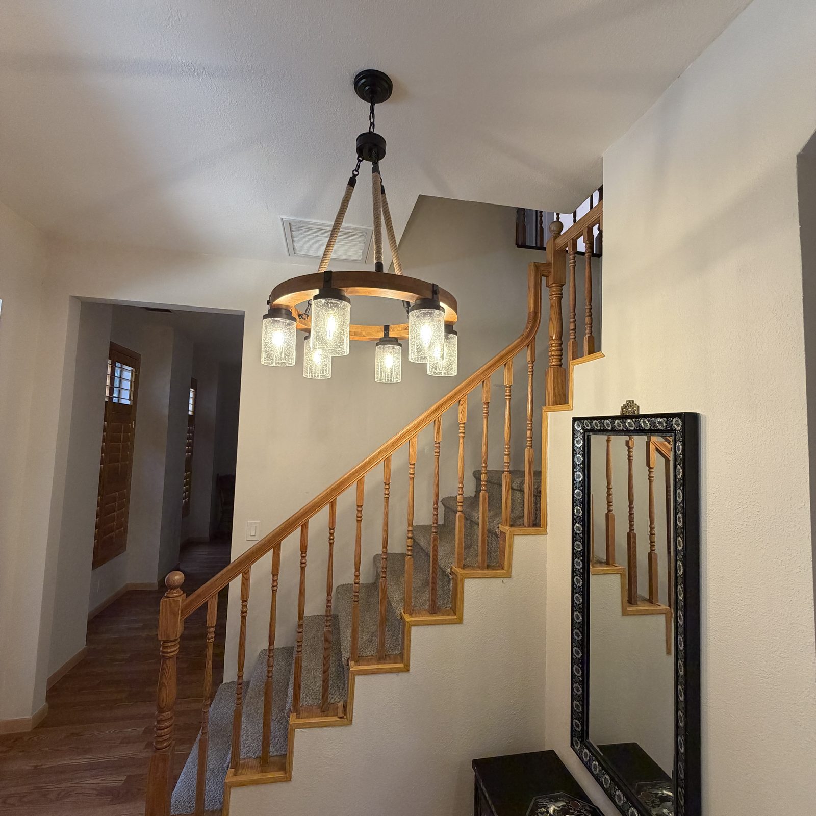 Rustic wheel chandelier installed over a two-story staircase